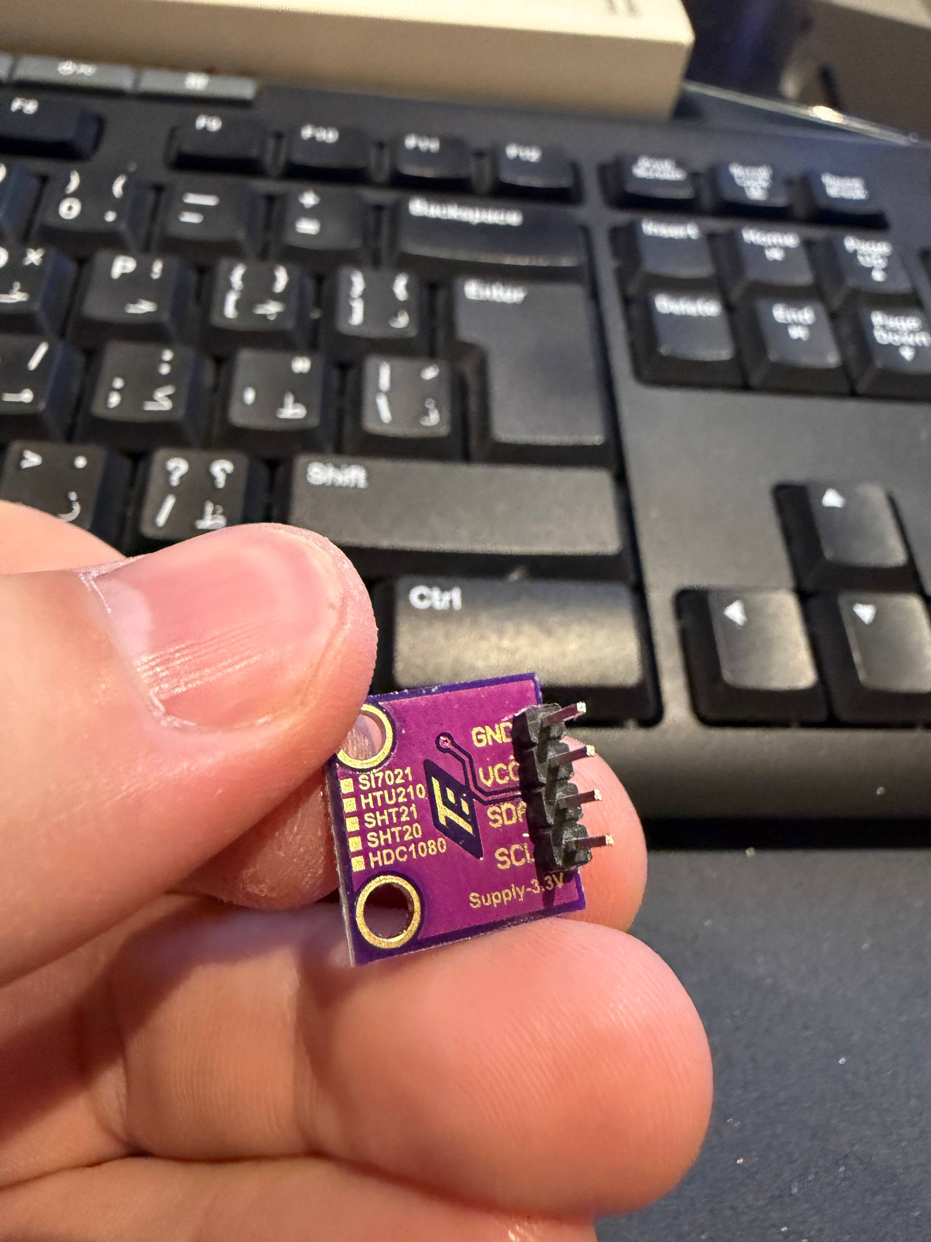 Close-up of a purple I2C humidity sensor breakout silkscreened SI7021 / HTU21D / SHT21 / SHT20 / HDC1080 — one board that can carry any of those chips; this one is an HDC1080 at address 0x40