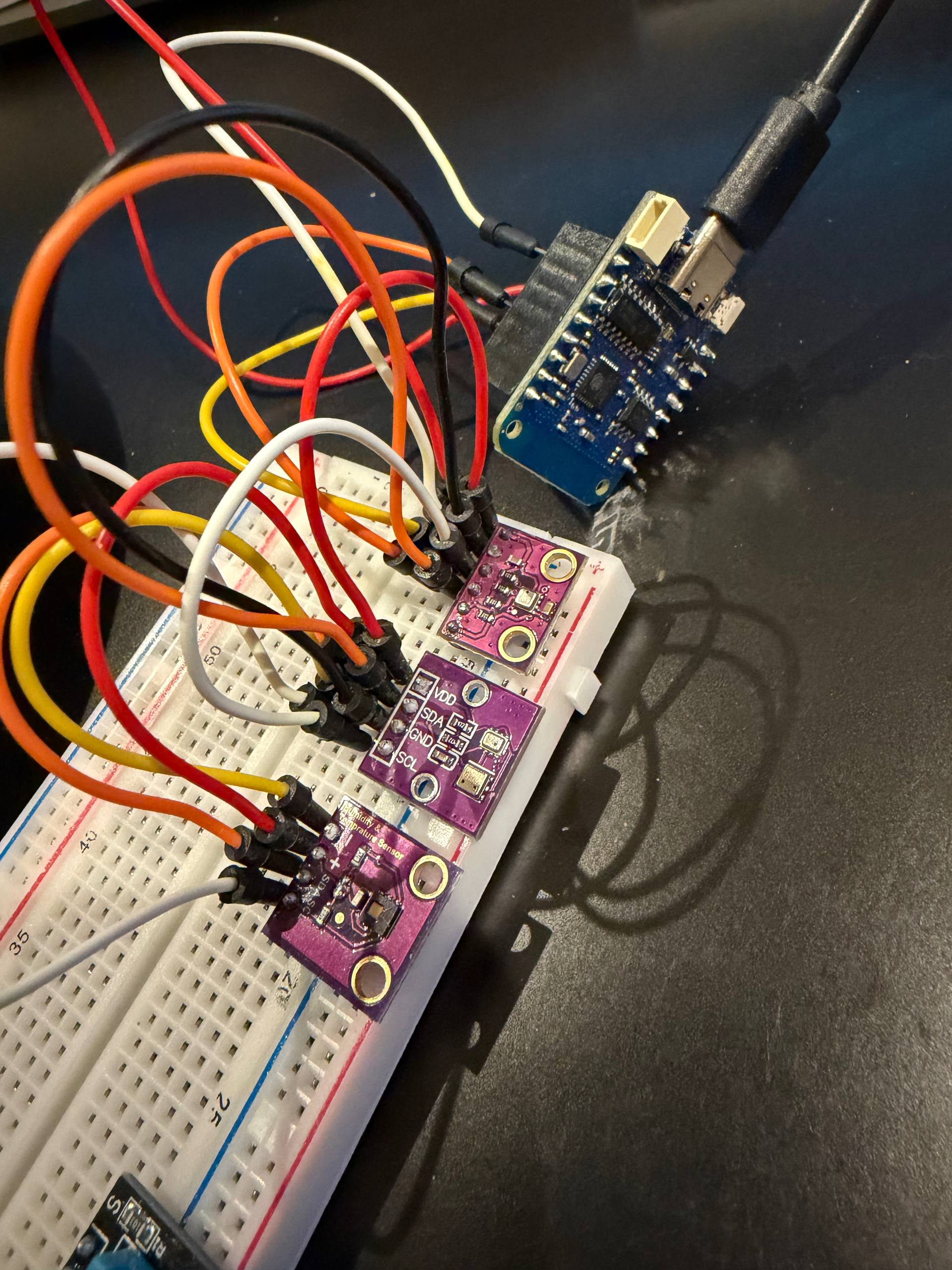 Four I2C sensor breakout boards on a breadboard — BME280, BMP280 and AHT20 purple modules plus an HDC1080, all wired to a small ESP board over shared SDA/SCL